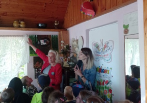 pani B. Kaszyńska pokazuje dzieciom stare przedmioty codziennego użytku zgromadzone w budynku, na ścianach wiszą starodawne przedmioty