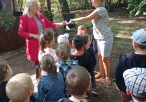 pani B. Kaszyńska podaje nauczycielce koszyczek, wokół stoją dzieci