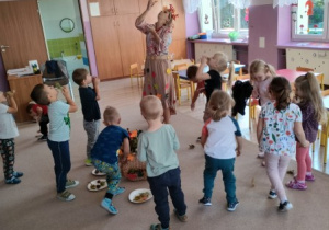 nauczycielka przebrana w jesienny stój prowadzi zabawę ruchową, obok są dzieci,