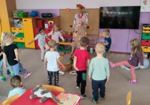nauczycielka przebrana w jesienny stój prowadzi zajęcie, wokół niej stoją dzieci