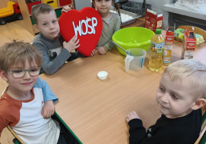 grupa dzieci przy stoliczku przygotowuje ciasteczka, na stole leżą składniki