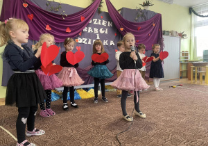 grupa dzieci ubrana odświętnie występuje z okazji Dnia Babci i Dziadka , w rączkach mająserduszka