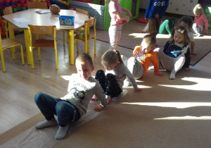 dzieci przechodzą po folii bąbelkowe mając stopy i dłonie na podłodze