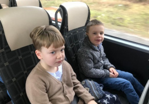 dwoje dzieci siedzi na fotelach w autokarze