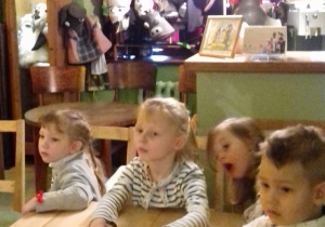 grupa dzieci siedzi przy stolikach