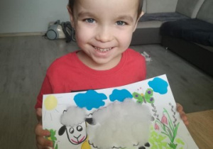 chłopiec prezentuje wykonany przez siebie obrazek owcy