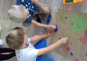 dwaj chłopcy pastelami rysują kropki