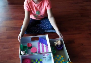 Dziewczynka prezentuje domek z pudełka