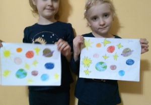 dwie dziewczynki prezentują prace plastyczne o tematyce kosmos