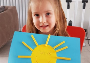 dziewczynka pokazuje wykonane przez siebie słoneczko