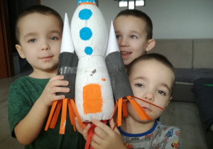 trzech chłopców pokazuje rakietę z butelek PET