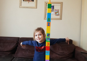 dziewczynka prezentuje wysoką rakietę zbudowaną z klocków