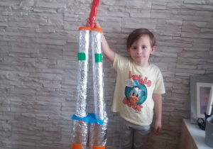 chłopiec prezentuje wykonaną przez siebie rakietę