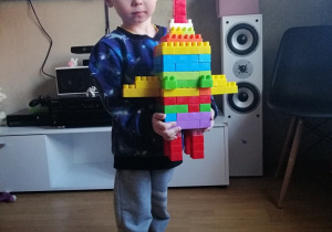 chłopiec pokazuje zbudowaną z klocków rakietę
