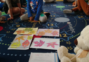 grupa dzieci na dywanie , jedno z nich układa logopedyczne obrazki
