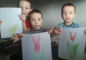 trzech chłopców trzyma namalowane tulipany