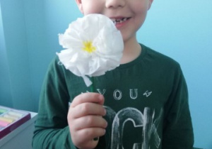 chłopiec pokazuje wykonany przez siebie wiosenny kwiat