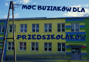 budynek przedszkola , a w jego oknach napis MOC BUZIAKÓW DLA PRZEDSZKOLAKÓW