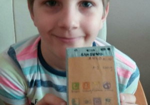 chłopiec prezentuje wykonany przez siebie telefon z kartonu