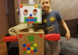chłopiec pokazuje wykonanego przez siebie robota z kartony