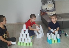trzej bracia układa wieże w kolorowych kubków