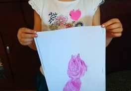 dziewczynka pokazuje narysowaną świnkę
