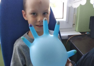 chłopiec prezentuje rękawiczkę z pomalowanymi "paznokciami"
