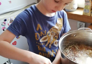 chłopiec przygotowuje w kuchni potrawę