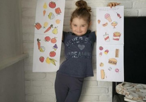 dziewczynka pokazuje przygotowane przez siebie plakaty o zdrowym odżywianiu