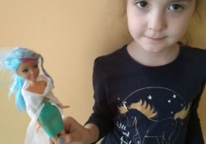 dziewczynka stoi z lalką w dłoni
