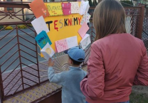 nauczycielka patrzy na plakat od dzieci zawieszony na bramie