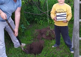 chłopiec i jego tata zakopują w ogrodzie rodzinną kapsułę skarbów