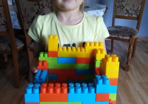 Dziewczynka pokazuje wykonaną z klocków budowlę