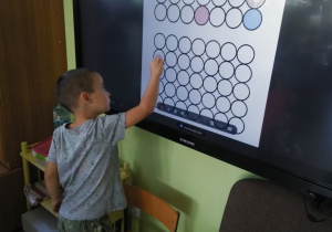 Chłopiec przy tablicy interaktywnej bawi się kropkami