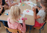 dzieci naklejają kolorowe kropki na papier