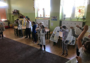 dzieci uczestniczą w zabawie rytmicznej z gazetami
