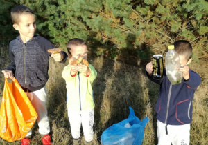 trzej bracia pokazują śmieci zebrane w lesie