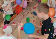 grupa dzieci odbija balonami zamoczonymi w farbie stemple na szarym papierze