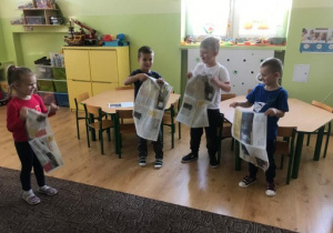 czworo dzieci stoi z gazetami w rękach - uczestniczą w zabawie