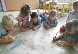 dzieci kolorują odrysowane wzory własnych dłoni
