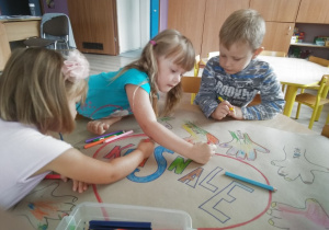 troje dzieci koloruje grupowy plakat