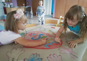 dwie dziewczynki kolorują serce na grupowym plakacie