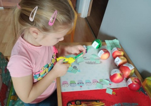 dziewczynka wykonuje matematyczną zabawe z wykorzystatniem owoców