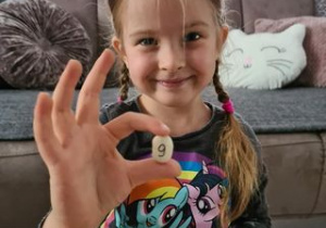 dziewczynka pokazuje znalezioną fasolkę z cyferką