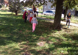 dzieci zbierają kasztany pod drzewem