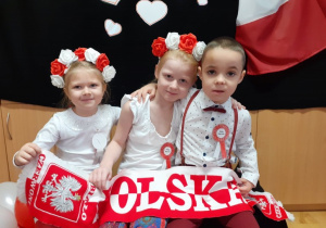 troje dzieci, z szalikiem "POLSKA" pozuje do zdjęcia