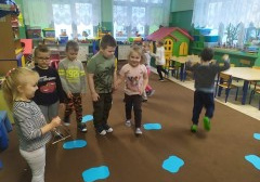dzieci podzielone na grupy, jedne grają na dzwonkach, inne przemieszczają się po dywanie