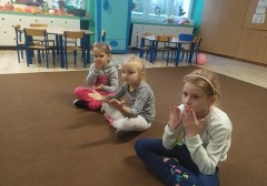 trzy dziewczynki siedzą na dywanie, wykonują ćwiczenia artykulacyjne