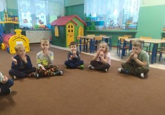 dzieci siedzą na dywanie, wykonują ćwiczenia artykulacyjne