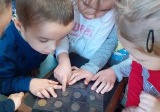 troje dzieci ogląda stare monety